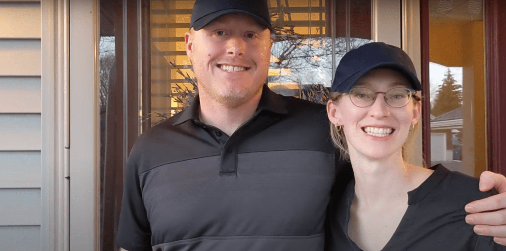 Laura and Matt Schuh, the founders of Northern Nest Home Watch, a home check company, stand together in front of a home in carver county.